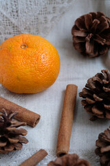 Obraz na płótnie Canvas tangerine, cinnamon sticks and pine cones on a napkin