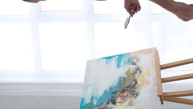 An artist paints a piece of art on a canvas with color oil painting at home. Vertical video