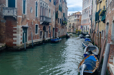 Fototapeta na wymiar One of canals with boats passing by residential buildings in Venice