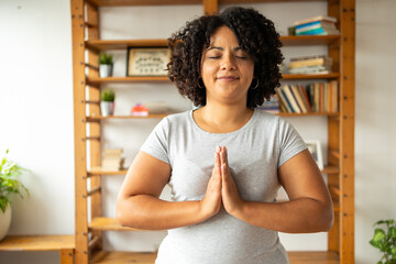 Smiling woman practicing yoga in prayer pose at home - obrazy, fototapety, plakaty