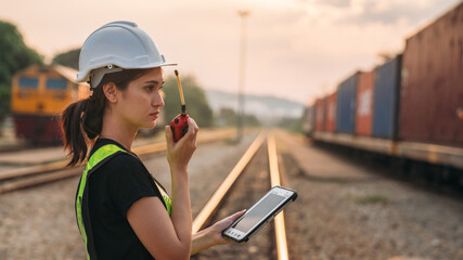 Foreman checking inventory or task details on freight train cars and shipping containers. Logistics...