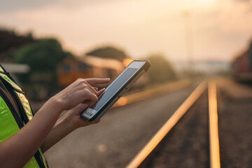 Foreman checking inventory or task details on freight train cars and shipping containers. Logistics...