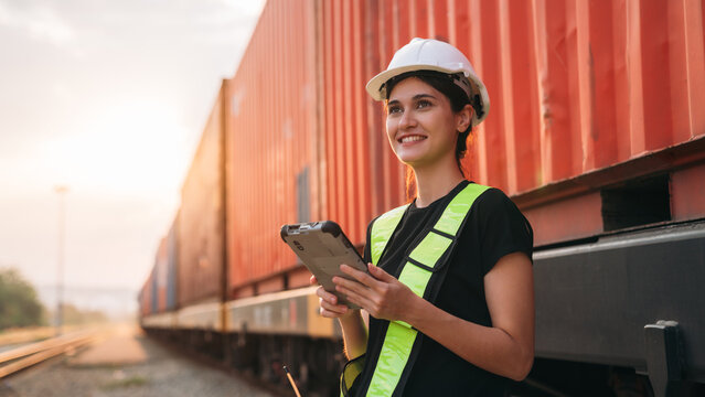 Foreman checking inventory or task details on freight train cars and shipping containers. Logistics concept, import, and export industries.