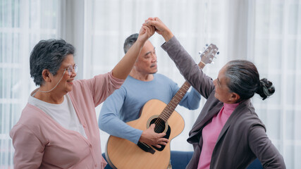 Senior friends are dancing and playing a musical instrument at residence. Asian senior's hobbies and interests. Senior lifestyle at home.