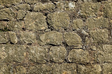 Background, texture of the wall of an ancient house made of natural mossy stone