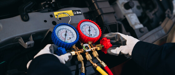 Close up hand of Mechanics inspect and check the refrigerant and fill the car air conditioner. Worker service car air conditioner.	