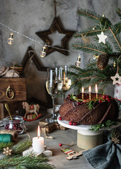 Christmas chocolate bundt cake decorated with cranberries and rosemary in festive moody composition dark key