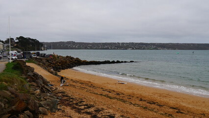 Promenade à la plage de la rade de Brest, sous un temps pluvieux, ciel gris, beaucoup de vent, détente de famille et de bien-être, avec installation côtière et de la végétation maritime