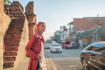 Gen z girl leather fashion with punk Asian woman tourist of local city Southeast Asia travel trendy pink hairstyle young female punk traveler walking around in town - obrazy, fototapety, plakaty