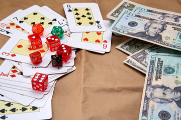 Poker cards, several dice of different colors and dollars lying on a cardboard-like surface.