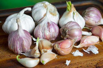 Garlic is a ripe, spicy product, a spice. It is essential in the preparation of many delicious dishes. On an old background in a composition with kitchen accessories.