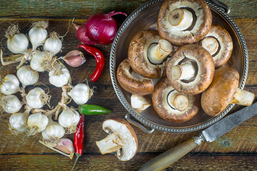 Champignon mushrooms, a fresh natural product, in a composition with kitchen ingredients, on an old background.