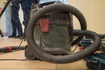 An industrial vacuum cleaner on a dusty floor in a building under construction and renovation.