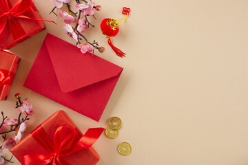Presents for the Lunar New Year festivities. Top view photo of festive gift boxes, red envelope, decor elements on beige background with advert placement