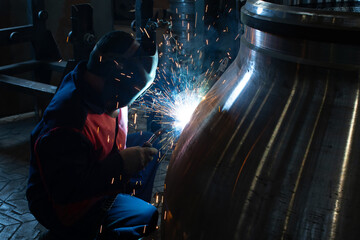 A welder works at a factory. Manufacturing of industrial steel valves.