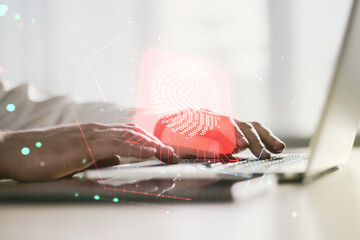 Double exposure of abstract creative fingerprint hologram with hands typing on laptop on background, research and development concept