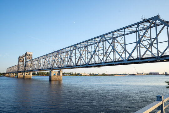 an old metal road bridge over a wide river against a blue sky background