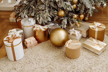 Christmas gifts under the Christmas tree at home. Beige and gold shades.