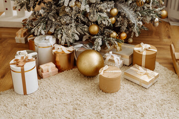 Christmas gifts under the Christmas tree at home. Beige and gold shades.