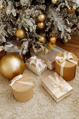Christmas gifts under the Christmas tree at home. Beige and gold shades.