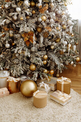 Christmas gifts under the Christmas tree at home. Beige and gold shades.