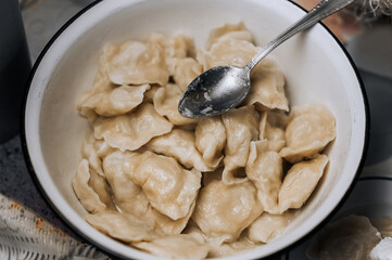 A large bowl with dumplings and a spoon is on the table. Village Ukrainian cooking traditions. Food...