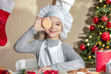 Cheerful girl closes her eye with Christmas gingerbread cookies in the shape of a ball.