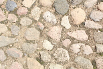 Stone background of cobblestones. An old paved stone road. Brutal background