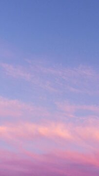 Time lapse of pink clouds and blue sky at sunset. Vertical Video