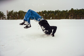 A teenager jumps while lying in the snow.