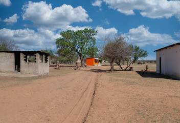Obraz premium african village, walk along a dirt road to an orange house, donkeys in the background