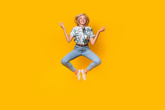 Full size photo of peaceful girl dressed print shirt stylish jeans levitating in meditation pose isolated on yellow color background - Powered by Adobe