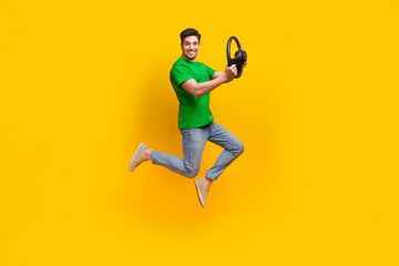 Fototapeta na wymiar Full length photo of optimistic satisfied man jumping with steering wheel in hands at driwing lessons isolated on yellow color background
