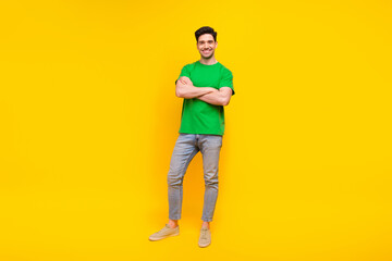 Fototapeta na wymiar Full length photo of optimistic pleasant nice man dressed green t-shirt jeans holding arms crossed isolated on yellow color background