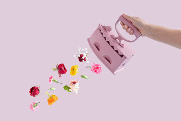 Women's hand holding Vintage Iron with flowers on a pink background. Iron clothes fashion idea. 