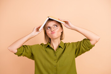 Photo of confused dissatisfied woman dressed green shirt hold book on head look empty space pouted...