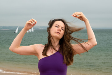 Portrait of a beautiful young brunette woman in purple dress on the beach