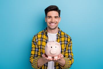 Fototapeta na wymiar Photo of satisfied cheerful businessman holding piggy bank he collect money to reach financial goal isolated over blue color background