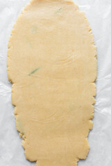 Top view of sugar cookie dough rolled between parchment paper, process of making cut out sugar cookies