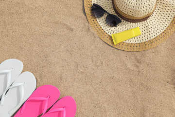 Flat lay composition with bright flip flops on sand. Space for text
