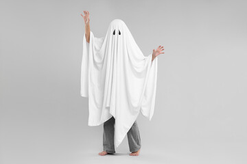 Woman in white ghost costume on light grey background. Halloween celebration
