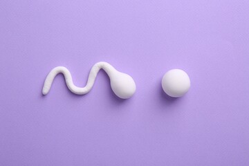 Fertilization concept. Sperm and egg cells on violet background, top view