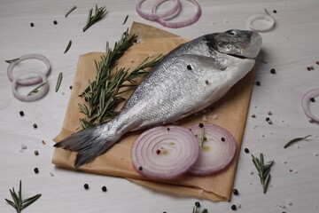 Raw dorado fish, spices and onion on white wooden table