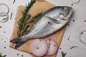 Raw dorado fish, spices and onion on white wooden table, flat lay