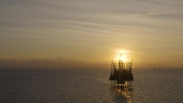 Aerial view of silhouette offshore jack up drilling rig during sunset - oil and gas industry
