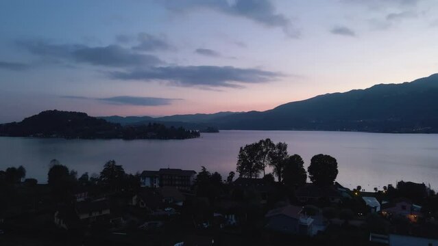 San Giulio Island within Lake Orta in Piedmont, Italy. aerial drone view at sunset blue hour. city lights and colorful sky