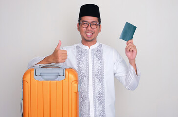 Moslem Asian man with suitcase smiling and give thumb up while showing passport