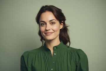 Portrait of beautiful young woman looking at camera and smiling while standing against green background