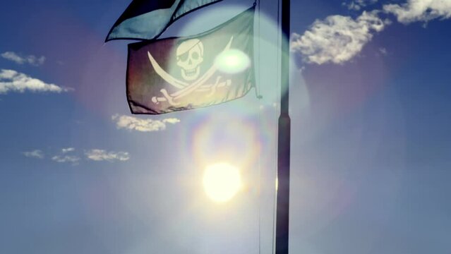 Pirate Flag Waving in the Wind Against Blue Sky with Clouds and with Sunlight and Lens Flare in Switzerland