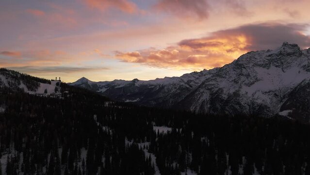 Winter season in Valmalenco of Valtellina at sunset, aerial drone backward view